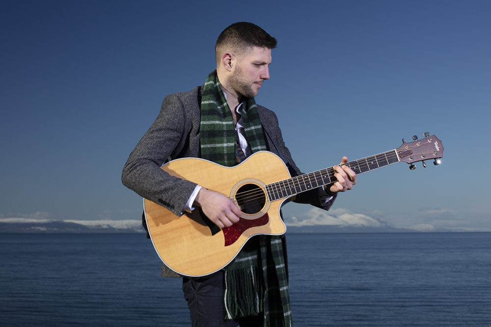 Musician Colm Keegan wearing the Rosemarkie waistcoat and a woven scarf by Alice Starmore