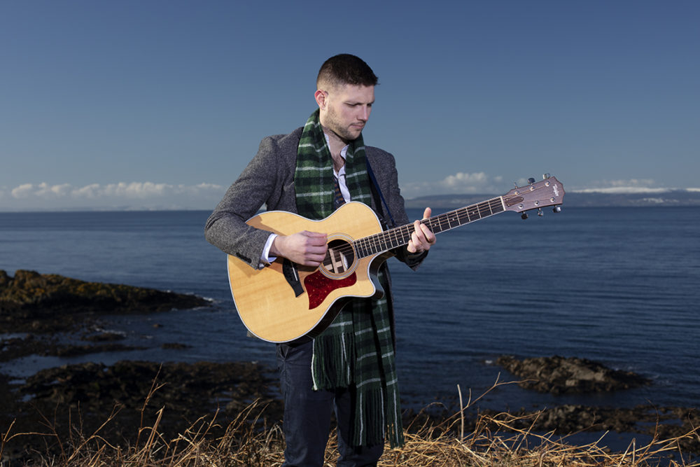 Musician Colm Keegan wearing the Rosemarkie waistcoat and a woven scarf by Alice Starmore