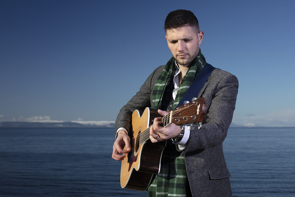 Musician Colm Keegan wearing the Rosemarkie waistcoat and a woven scarf by Alice Starmore